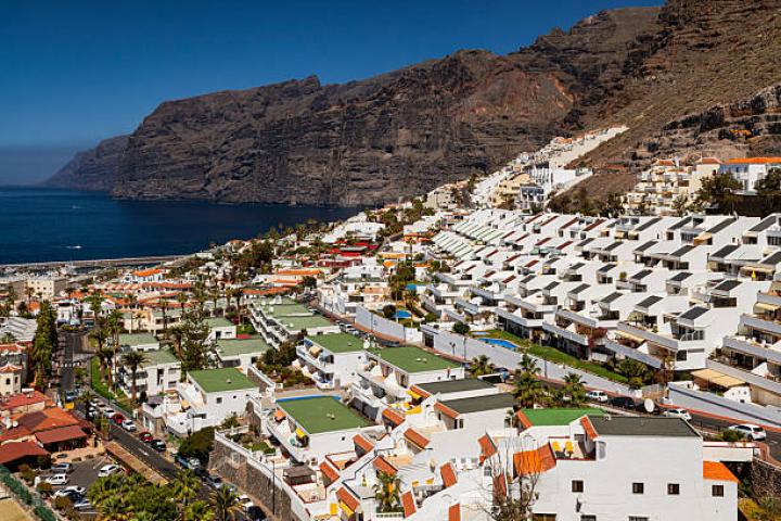Panoramic view of Los Gigantes in Tenerife, with white terraced buildings and dramatic cliffside by the ocean.