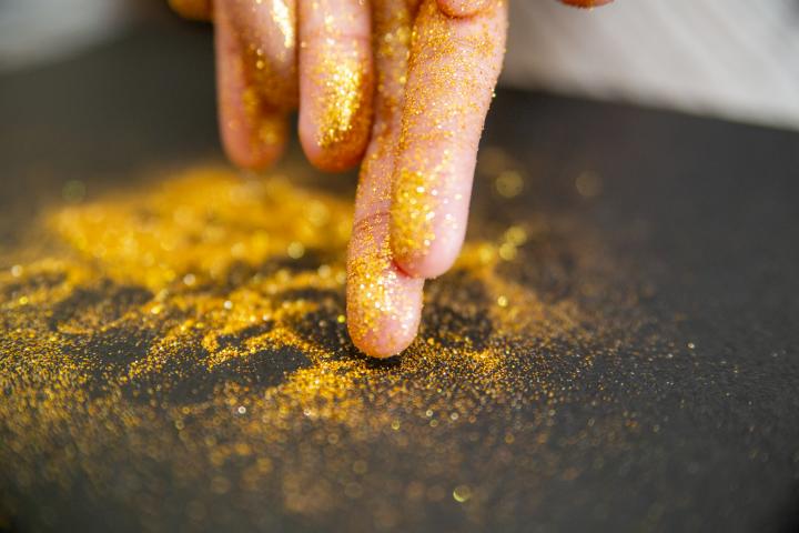 Polvo dorado reluciente en las manos