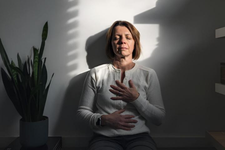 Una mujer adulta meditando bajo los últimos rayos de sol que entran en la habitación