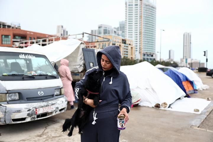 Samah Hjola, de 33 años, desplazada de los suburbios del sur de Beirut, sostiene a un perro el día en una zona de tiendas de campaña en el centro de la ciudad, el 20 de marzo de 2026.