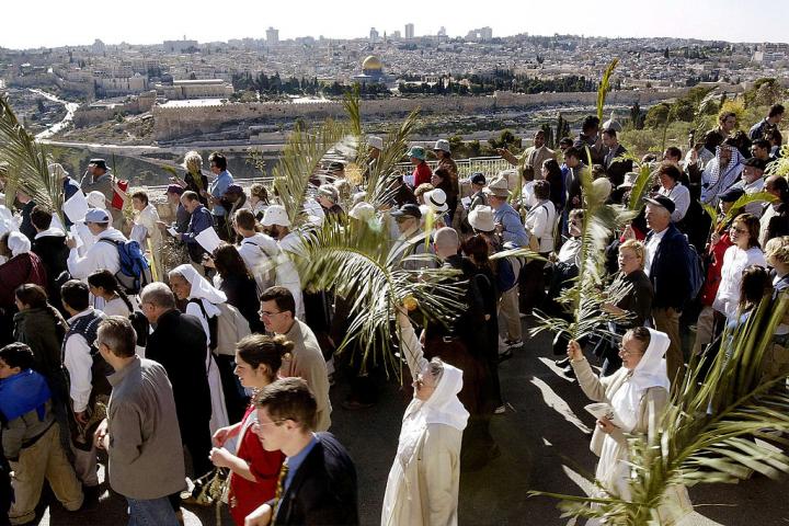 Fieles cristianos siguen los pasos de Jesús el 4 de abril de 2004, portando ramas de palma y olivo a lo largo del Monte de los Olivos durante la procesión del Domingo de Ramos.