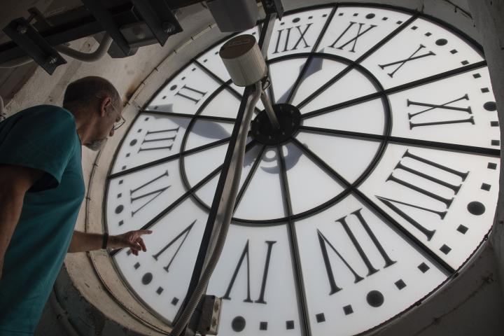 Un hombre cambia la hora en el reloj de una iglesia de Buñola, en Baleares.