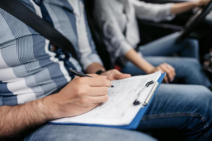 Un instructor evaluando a una joven en el permiso de conducir