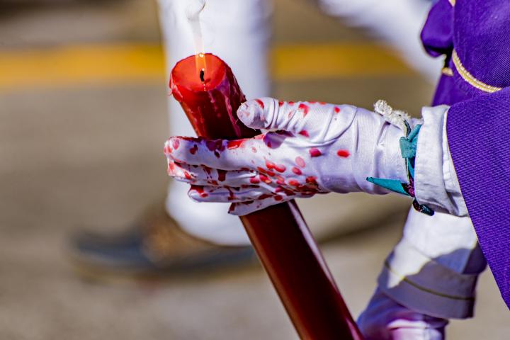 Un nazareno sujetando un cirio