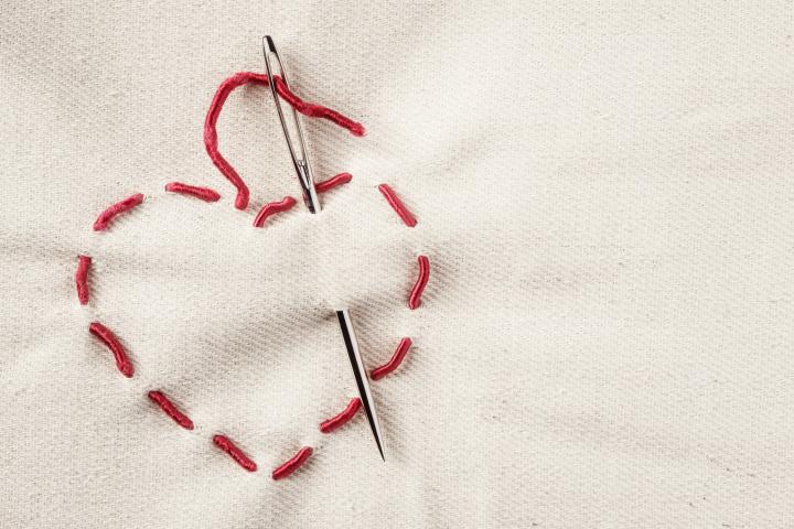 Símbolo de corazón hecho de hilo rojo sobre fondo de lienzo