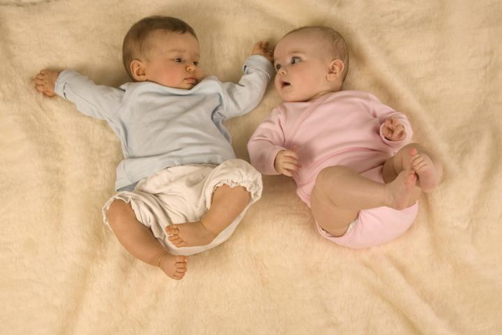 Un bebé vestido de azul y otro de color rosa