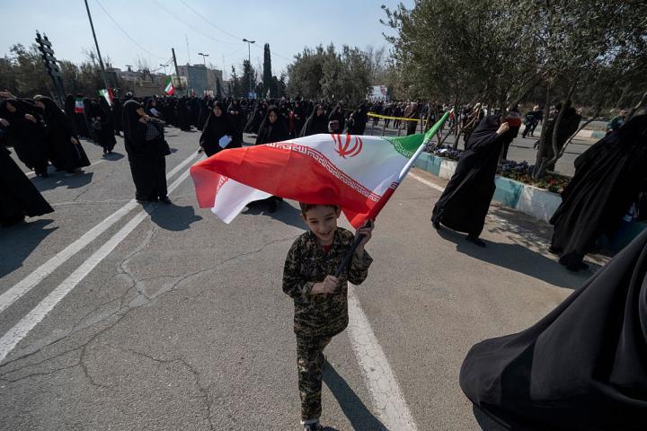 Un niño iraní vestido con uniforme militar porta una bandera nacional ante la Gran Mezquita Imam Jomenei, antes de las oraciones del viernes, en Teherán, el 6 de marzo de 2026.
