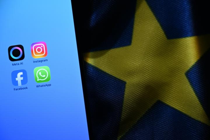 Un móvil con varias aplicaciones de Meta en la pantalla junto a una bandera de la Unión Europea