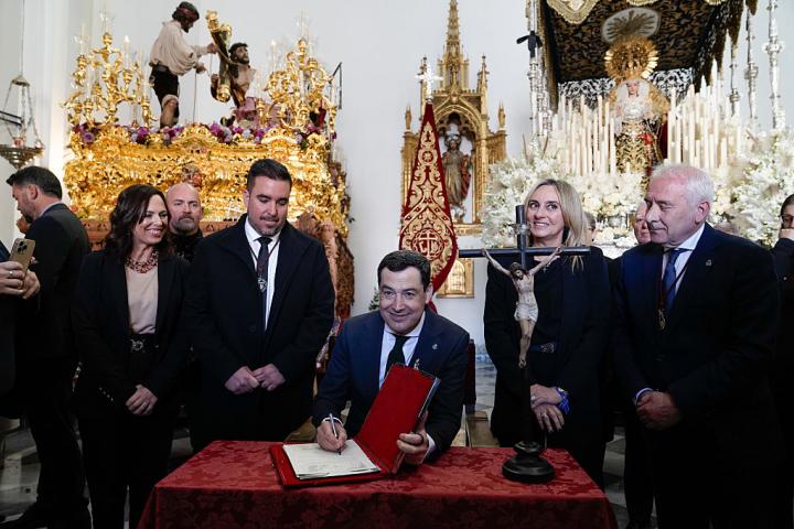 GRANADA ANDALUSIA,, SPAIN - MARCH 30: The president of the Junta de Andalucia, Juanma Moreno (c), signs in the book of honour after visiting this Easter Monday the Hermandad de Caridad del Santisimo Cristo del Trabajo y Nuestra Señora de la Luz at its headquarters in the Parroquia del Corpus Christi in Granada. On the 30th of March 2026 in Granada (Andalusia, Spain). On another Easter Monday, the Zaidin neighbourhood of Granada will see its Holy Christ of Labour, followed by his mother Our Lady of Light, make his penitential procession from his home parish of Corpus Christi to the Holy Cathedral. Easter Monday in Granada is completed with four more brotherhoods: El Huerto, Los Dolores, El Rescate and San Agustin. (Photo By Arsenio Zurita/Europa Press via Getty Images)