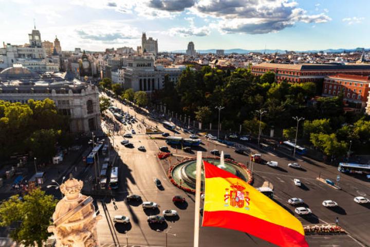 Waving Spanish flag and Plaza de Cibeles. Madrid, capital of Spain.
