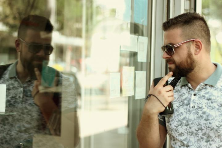 Retrato de un joven barbudo caminando por la calle y mirando los escaparates.