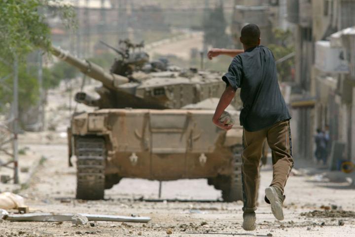 Un joven palestino lanza piedras a un tanque israelí durante enfrentamiento, el 8 de mayo de 2003, en el campo de refugiados de Balata, en Cisjordania.