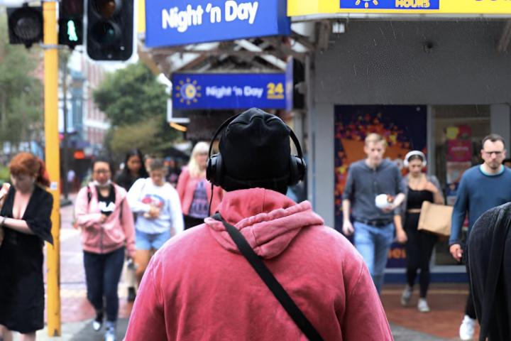 Un joven con auriculares caminando por una calle llena de gente