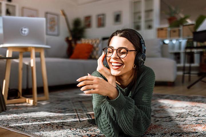 Portrait of a beautiful young woman smiling and relaxing on the living room floor while listening to music.