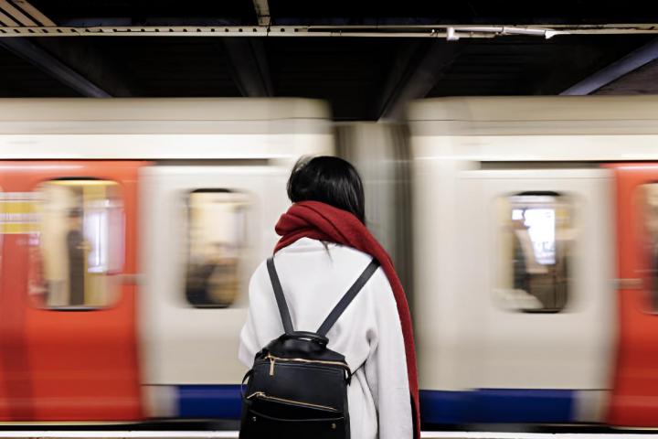 Mujer joven esperando la llegada del tren en la estación de metro.