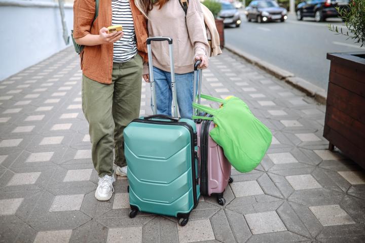 Dos turistas, con sus maletas en una calle.