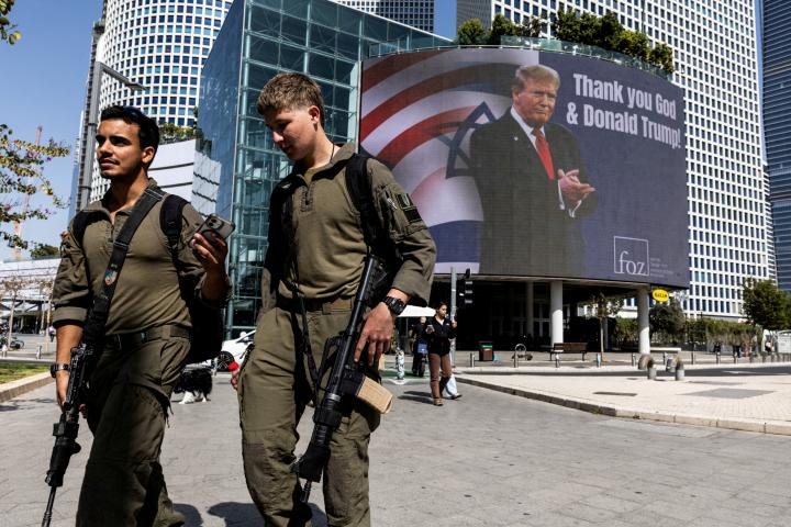 Soldados israelíes pasan junto a un anuncio pagado por un grupo evangélico, con el presidente de EEUU, Donald Trump, y el lema: "Gracias a Dios y a Donald Trump", el 12 de marzo de 2026, en Tel Aviv.
