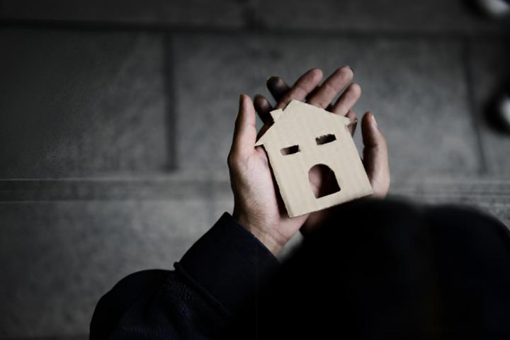 Una persona pobre sosteniendo una casa de papel en sus manos