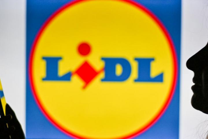Una persona usando su teléfono móvil junto al logo de Lidl