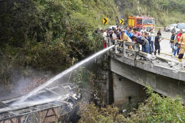 Fotografía cedida por Bomberos Cuenca que muestra a sus integrantes atendiendo el accidente de un autobús que se precipitó a un abismo y posteriormente se incendió, el 16 de abril de 2026, en Ecuador.