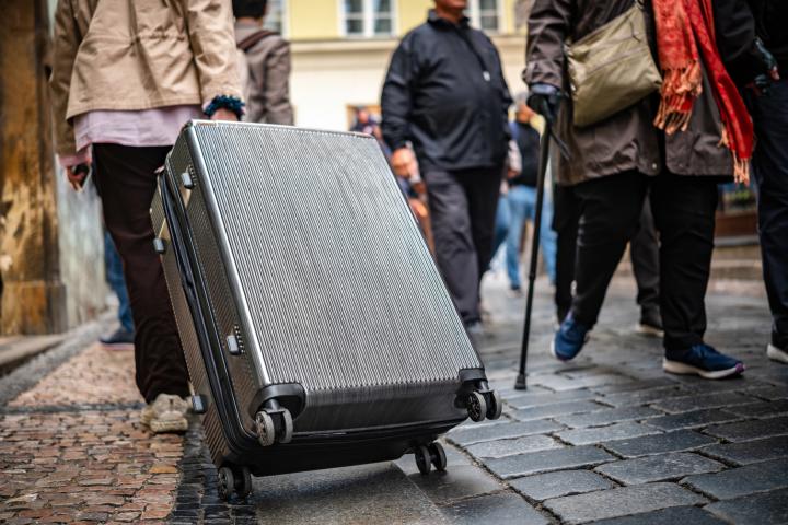 Un turista, paseando con una maleta por la calle de una ciudad.