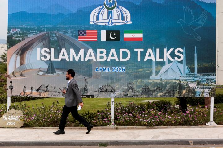 Un hombre pasa junto a una valla publicitaria de las reuniones de EEUU e Irán, cerca del centro de prensa especial instalado en Islamabad (Pakistán), el 11 de abril de 2026.
