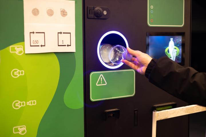 Una persona introduciendo una botella de plástico en una máquina de reciclaje, en una imagen de archivo