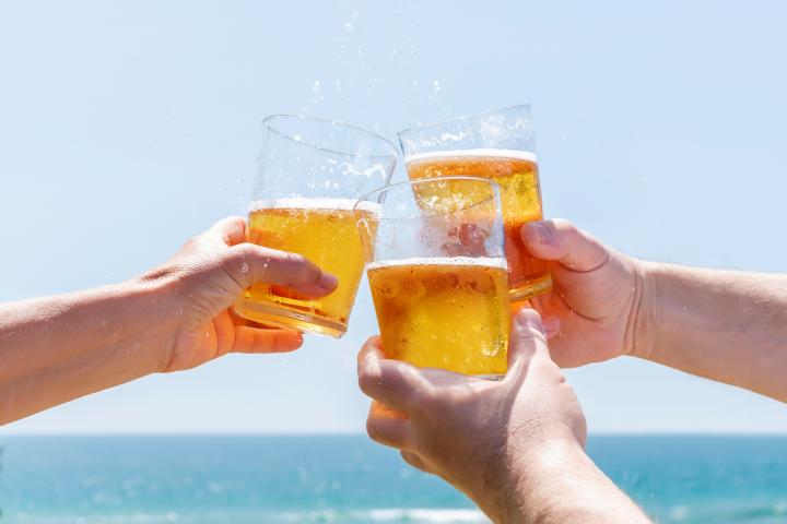 Varias personas beben cerveza en una playa.