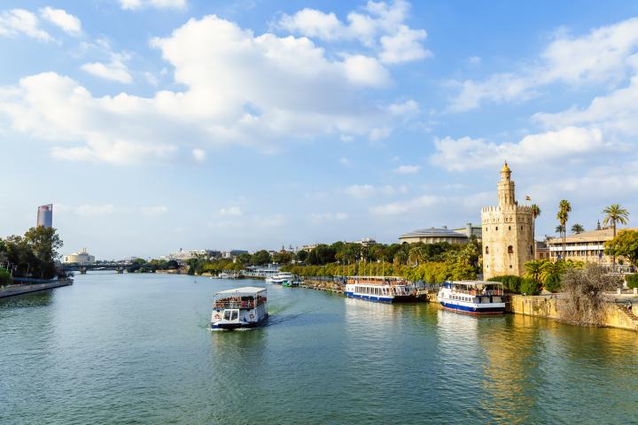 Paisaje urbano de Sevilla con el río Guadalquivir, la Torre del Oro y la Torre Sevilla."