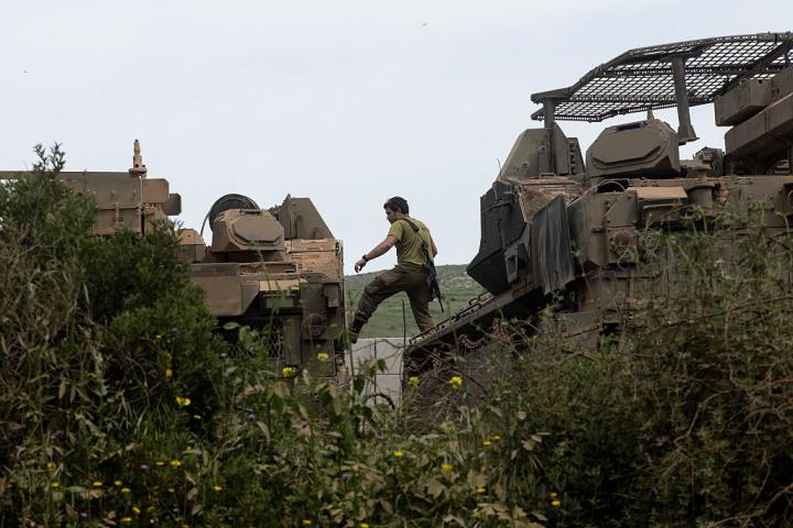 Un soldado israelí salta entre vehículos blindados cerca de la frontera con Líbano, el 17 de abril de 2026, en el norte de su país.