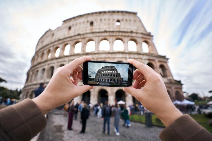 Una persona, haciendo una foto al Coliseo de Roma.