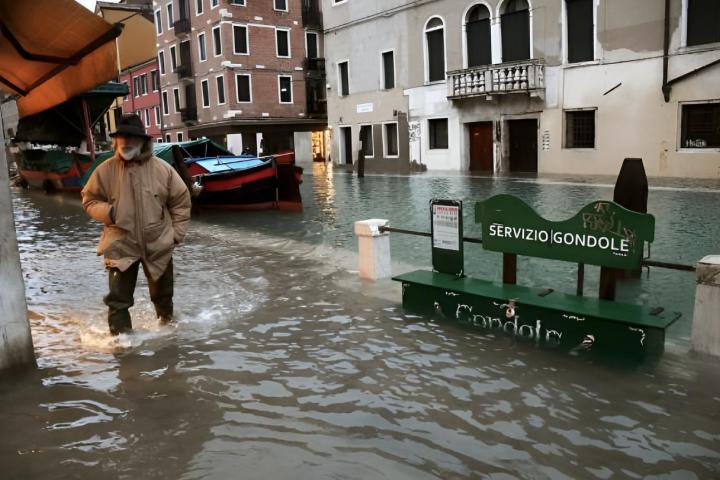 Un hombre caminando por un canal inundado de Venecia
