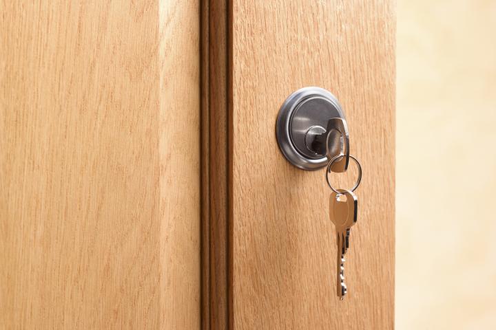 Una llave puesta en la cerradura de una casa