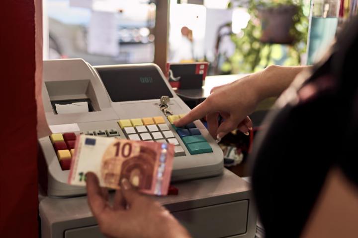Una mujer metiendo 10 euros en la caja del trabajo.