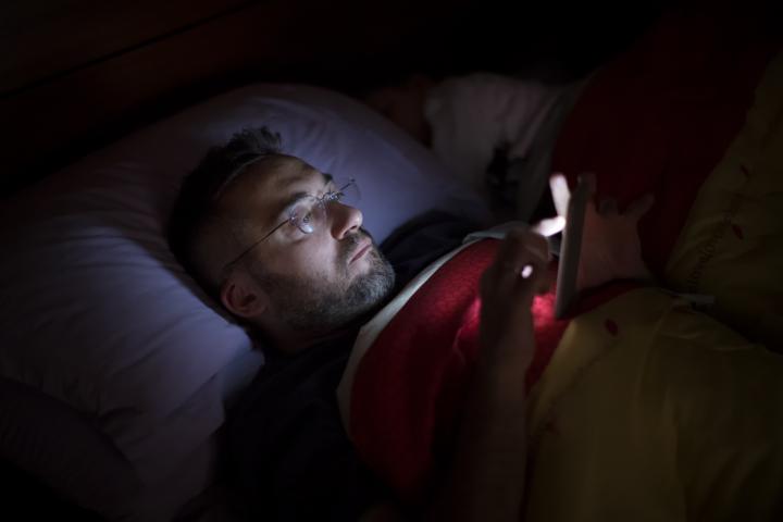 Un hombre usando el móvil en la cama antes de dormir