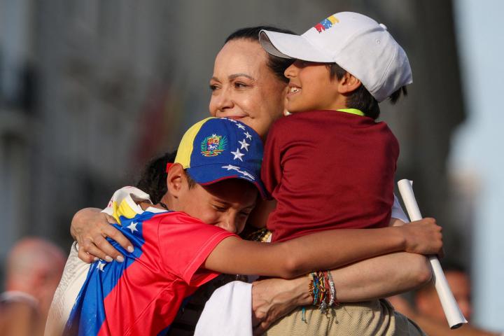 La líder de la oposición venezolana, María Corina Machado, abraza a unos niños durante un mitin en Madrid, en el marco de su visita a España, el 18 de abril de 2026.