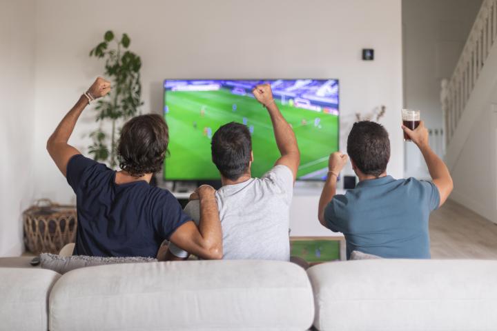 Tres personas viendo un partido de fútbol.