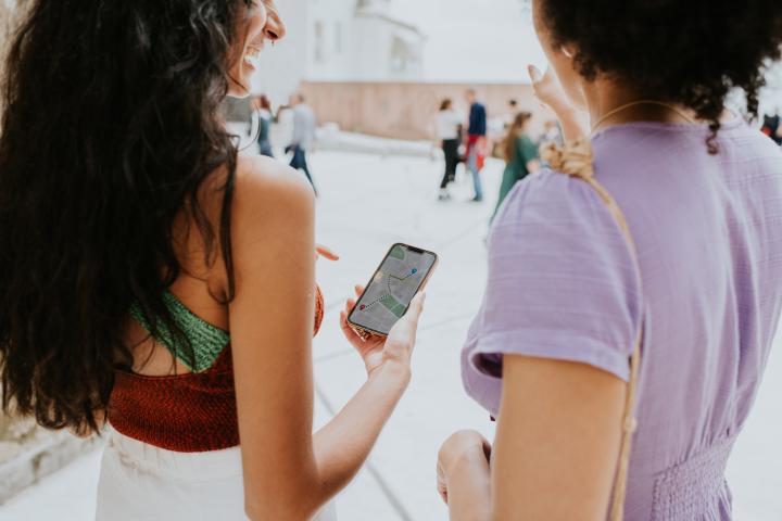 Una mujer de vacaciones usa su teléfono inteligente para obtener indicaciones mientras camina.