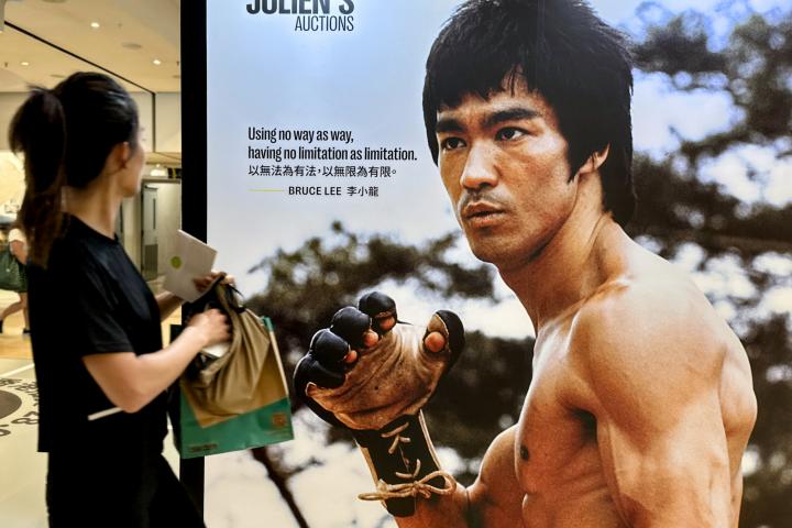Una visitante junto a un póster de Bruce Lee durante "Leyendas en movimiento" de Julien's Auctions, en Pacific Place el 14 de septiembre de 2024 en Hong Kong, China.