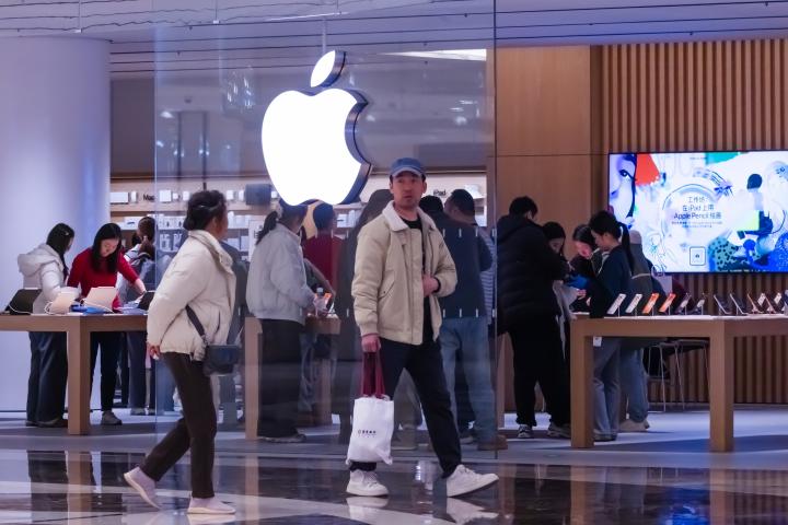 Clientes pasean junto a una tienda Apple de un centro comercial en China.