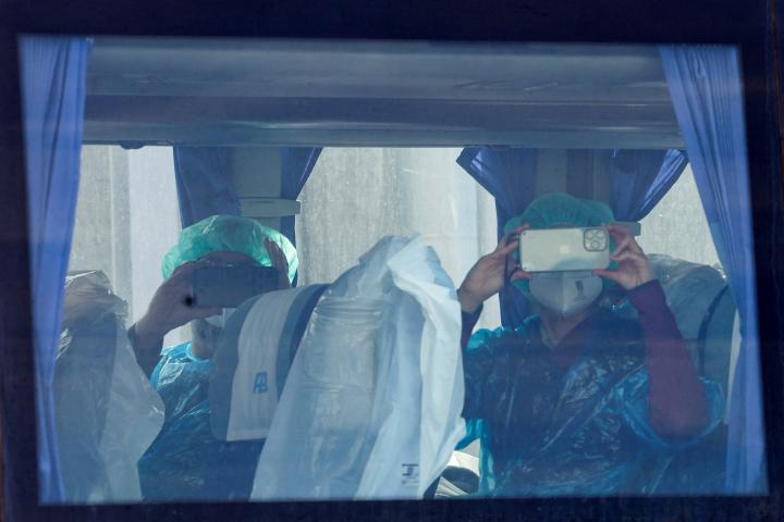 Dos pasajeros del MV Hondius, haciendo fotografías desde el autobús de la UME.