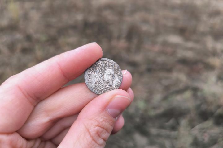 Foto de archivo de un arqueólogo, tras encontrar una moneda antigua.