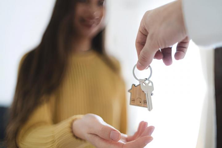 Una mujer recibiendo la llave de su nuevo hogar en un salón luminoso