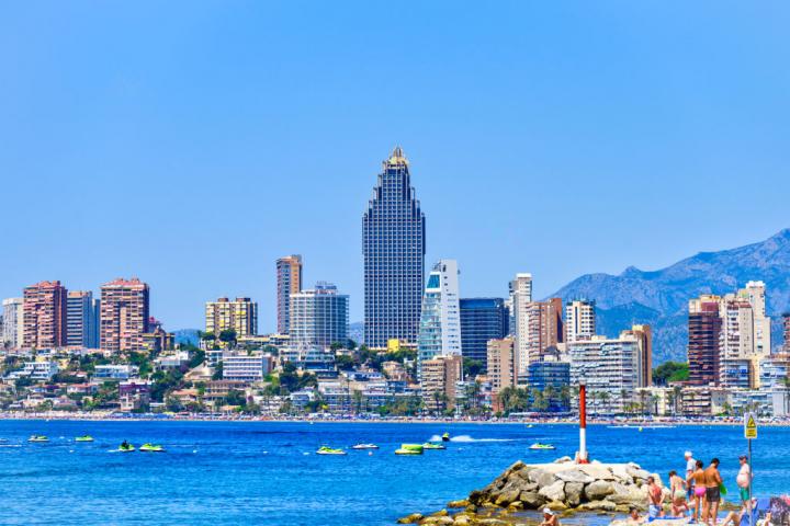 BENIDORM, ALICANTE, SPAIN - 2022/11/03: People on a rock by the beach with skyscrapers in the urban skyline of the famous city. (Photo by Roberto Machado Noa/LightRocket via Getty Images)