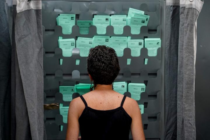 Una mujer observa varias papeletas en una cabina de votación en las elecciones andaluzas de 2022, en una imagen de archivo.