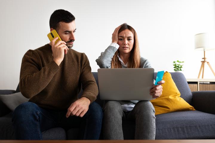 Un hombre habla por teléfono y su mujer usa el ordenador