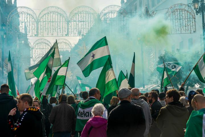 Cientos de personas en una manifestación andalucista en Sevilla en 2022: el ambiente es verde porque se han encendido bengalas y varias personas llevan banderas andaluzas