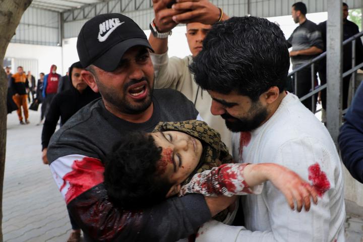 Dos adultos palestinos transportan el cuerpo de Yahya Al-Malahi, de tres años, que murió por un ataque israelí, en la ciudad de Gaza, el 14 de abril de 2026.