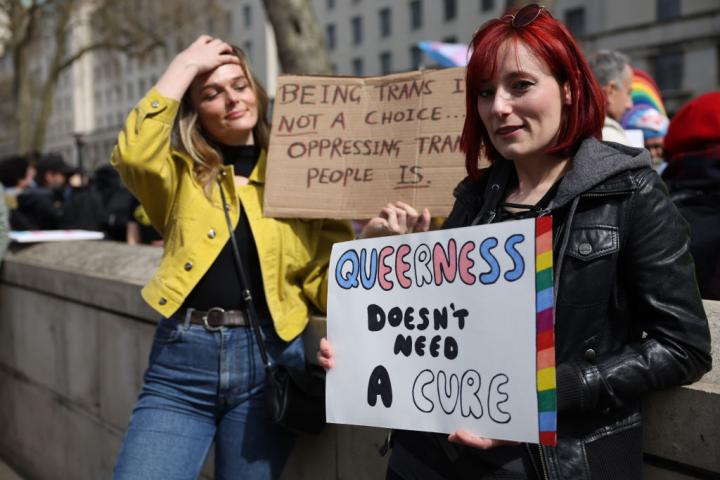 Manifestantes portan pancartas en las que se lee "la identidad queer no necesita cura", frente a Downing Street, el 10 de abril de 2022 en Londres (Reino Unido).