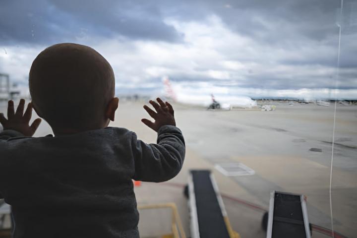 Un bebé de apenas un año asomado a la ventana de un aeropuerto